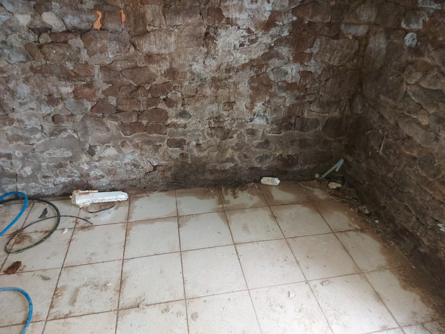 Venues d'eau en pied de mur en pierres, enterré de 30 cm, par absence de drainage extérieur